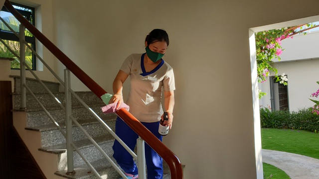 Nhân viên lau tay vịn cầu thang bằng dung dịch sát khuẩn